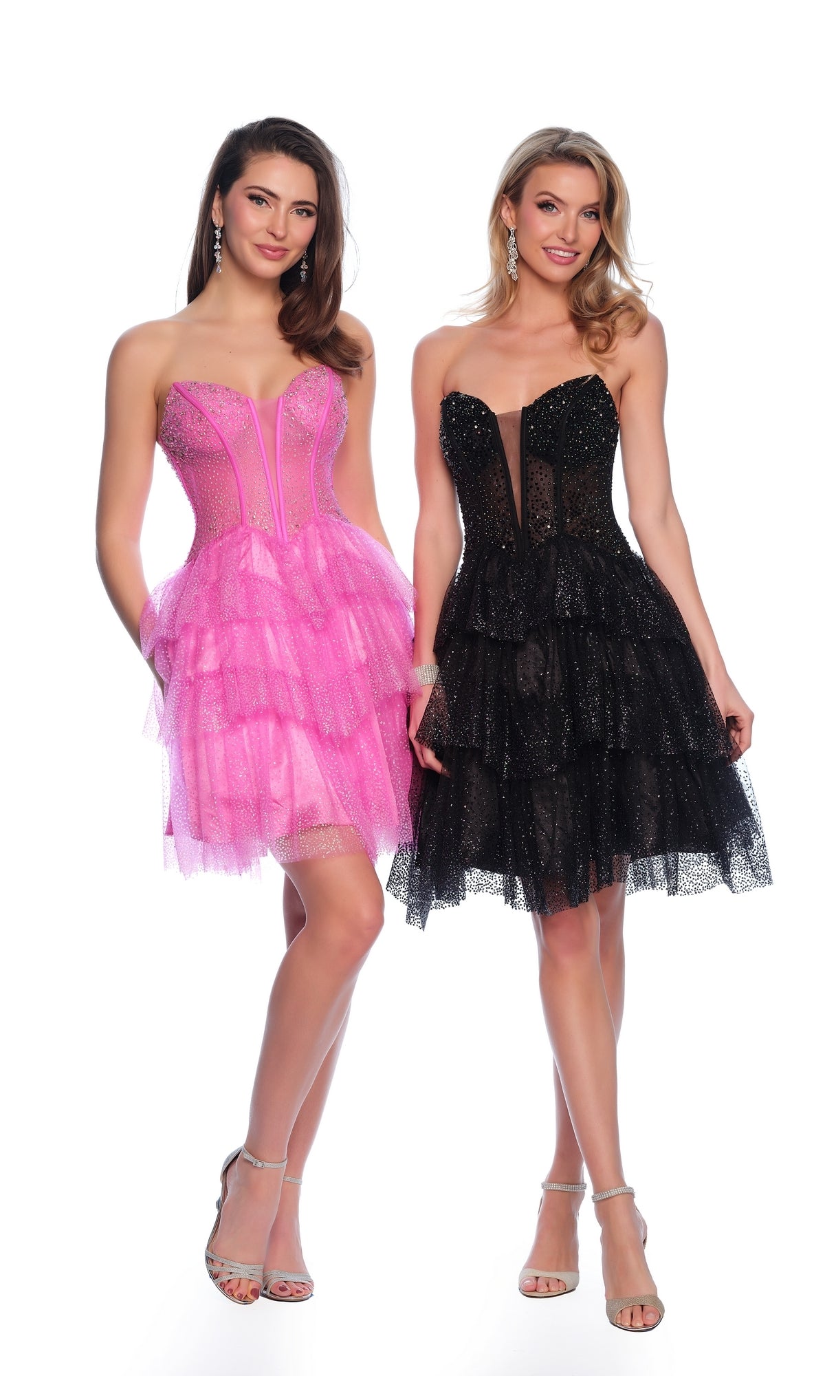 Two women stand together, one in the Dave & Johnny Short Glitter Hoco Dress 11878—a pink strapless layered tulle dress—while the other wears a black party dress with a sheer panel and matching layered tulle.